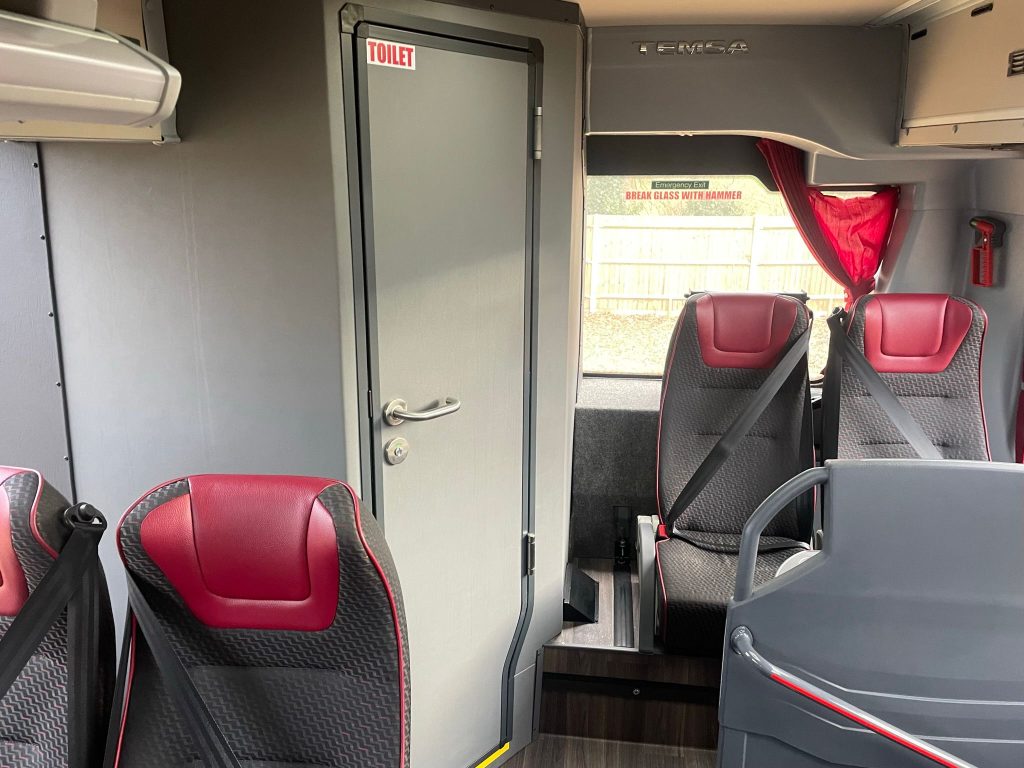 interior of a 34 seater coach showing the toilet door at the rear of the coach